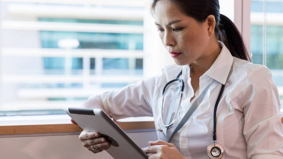 Vrouwelijke arts die op een tablet kijkt.