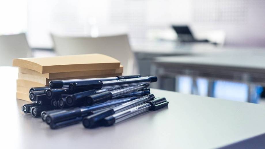 notitieblokjes en pennen op een tafel in een klaslokaal